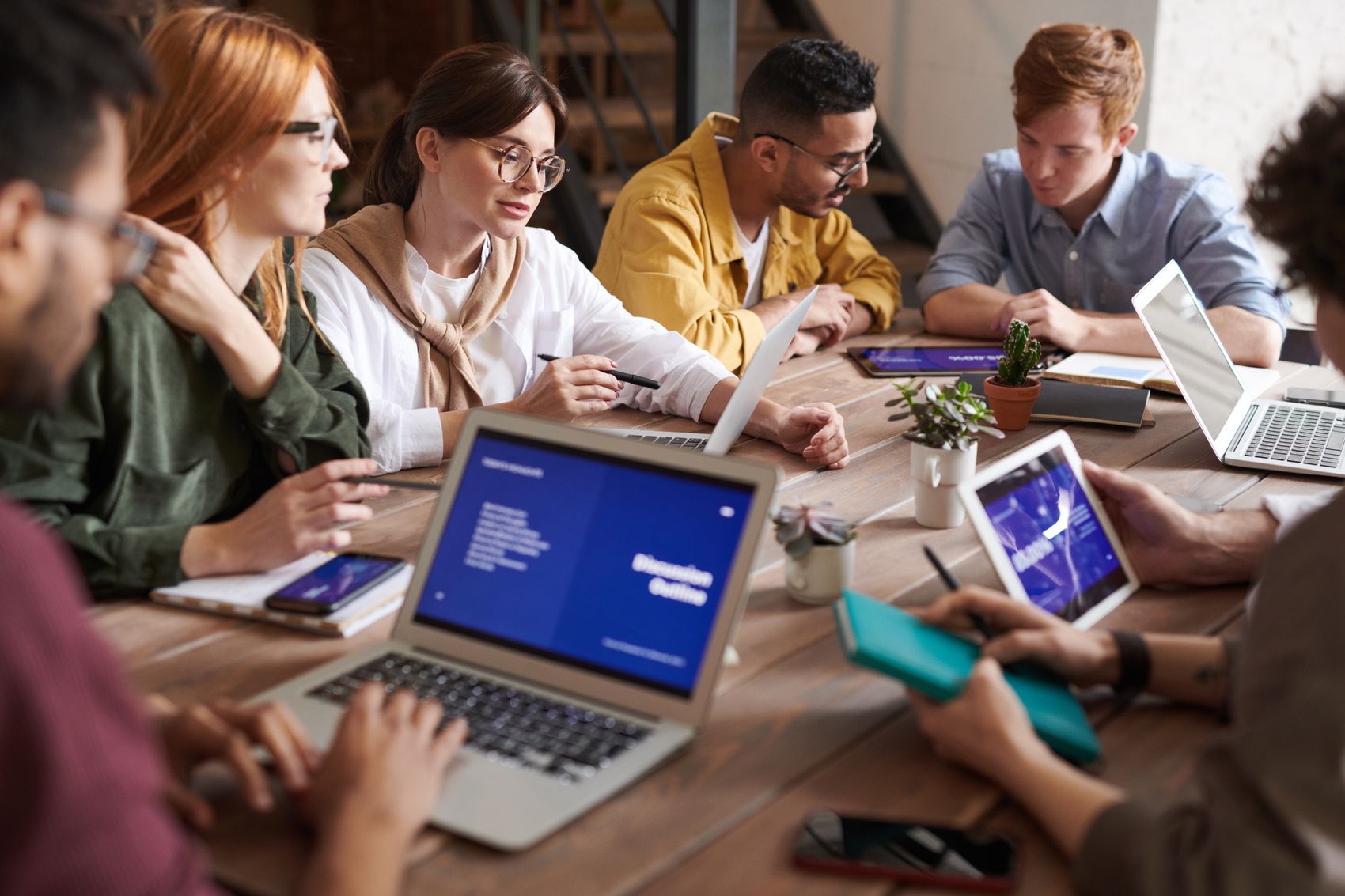 Nonprofit team gathered around a table planning a one-week fundraising campaign on laptops