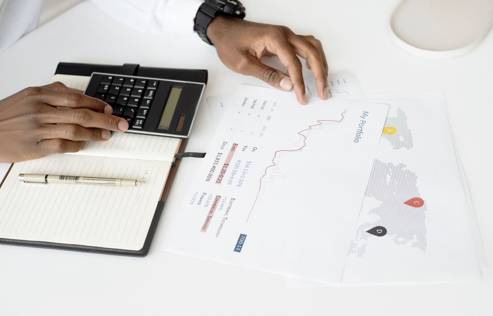 Hands using a calculator beside financial documents